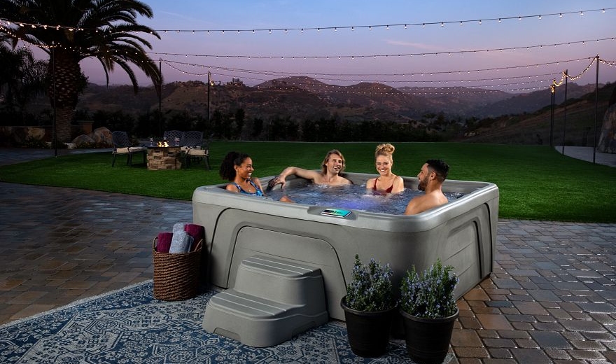 Group of people sitting in hot tub at sunset